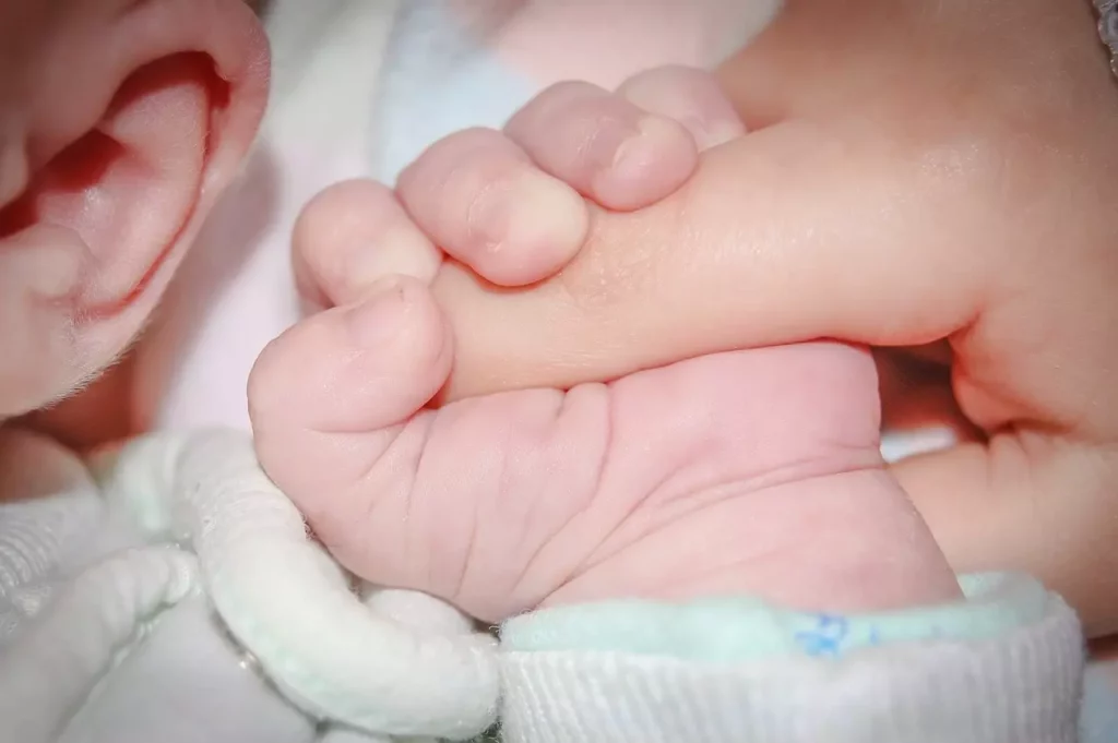 maternage proximal maman et bébé: bébé serra la main de maman