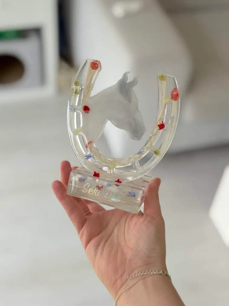 Fer à cheval en résine avec crins de cheval tenu dans la main
