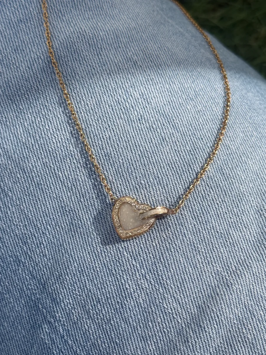 Collier cœur au lait maternel posé sur un jean