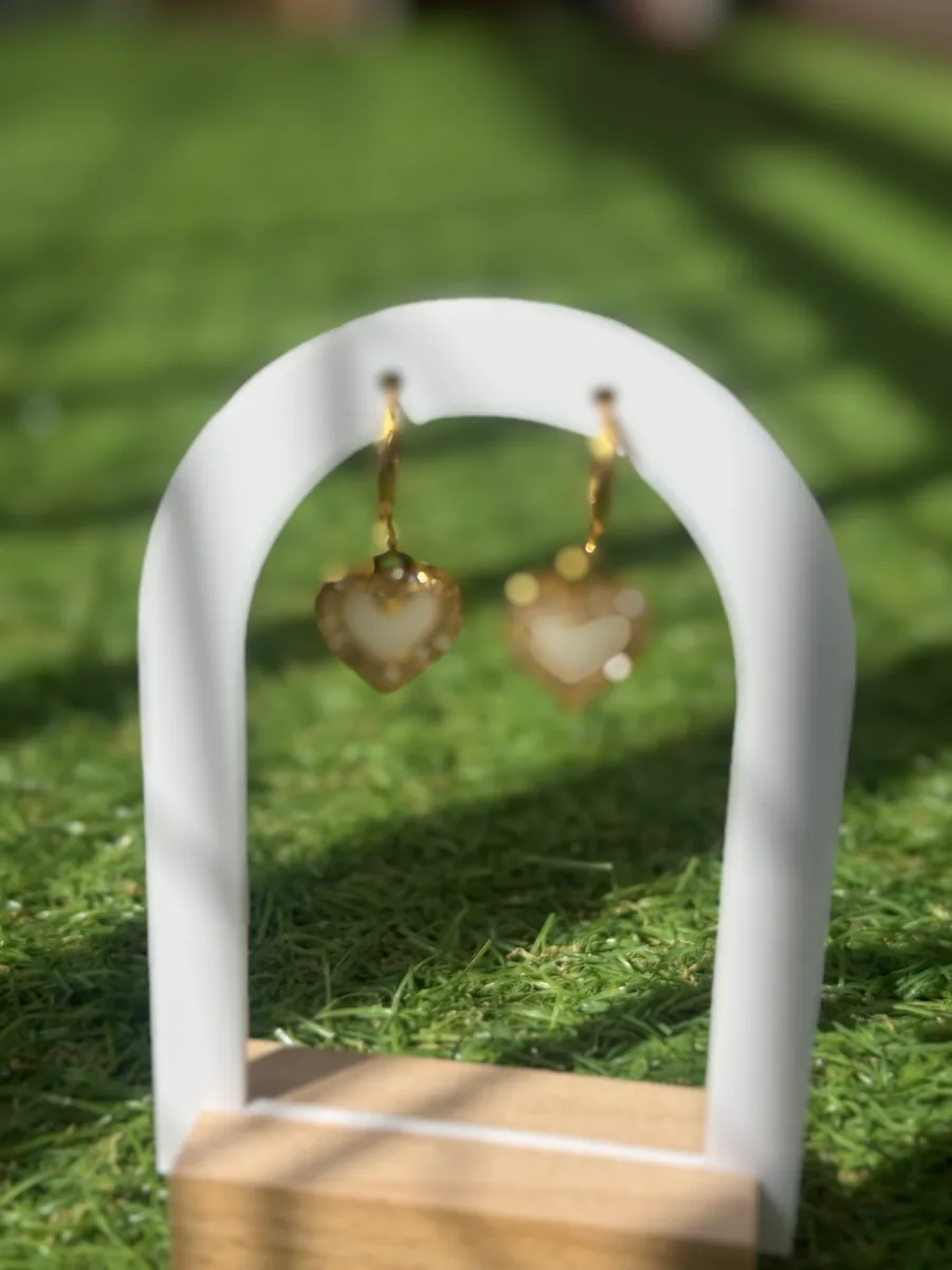 Boucles d'oreilles cœur au lait maternel sur un présentoir en arche