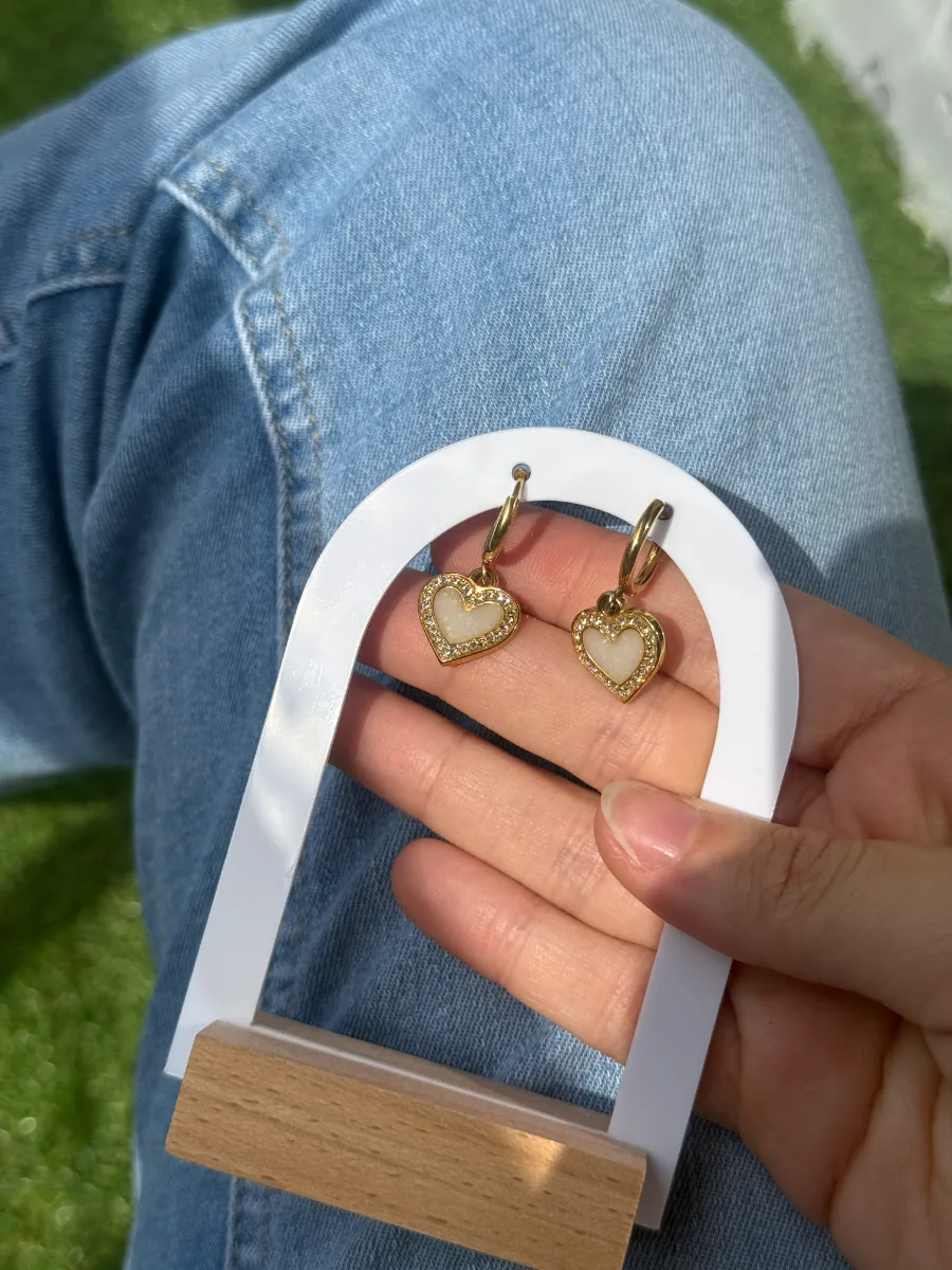 Présentoir en arche avec boucles cœur au lait maternel, posé sur un jean