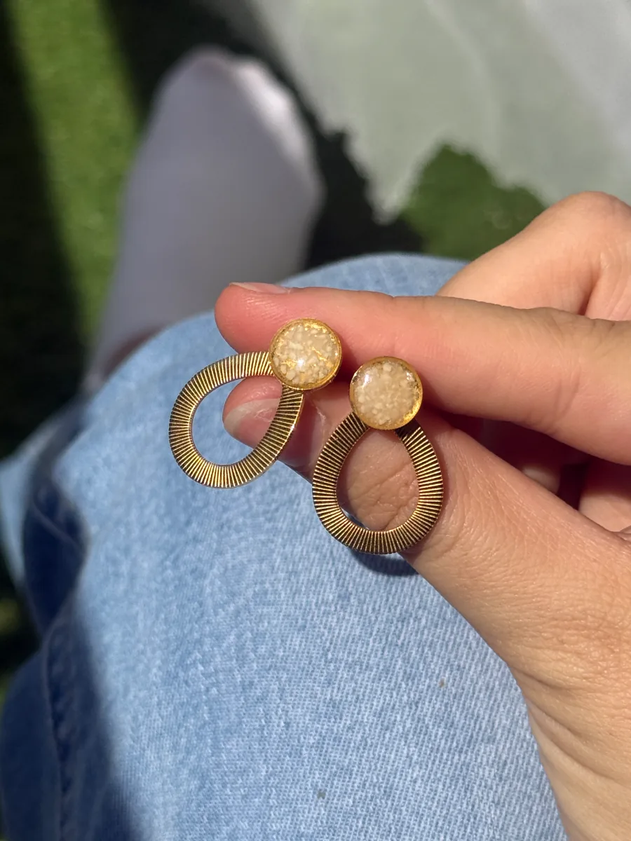 Boucles d'oreilles gouttes au lait maternel tenues dans la main