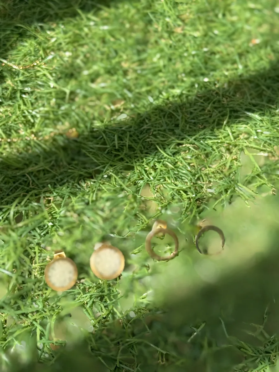Boucles d'oreilles au lait maternel, puces rondes et anneaux dorés sur l'herbe