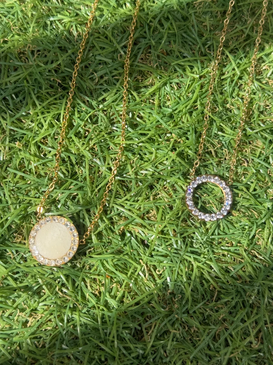 Colliers au lait maternel ronds sur chaînes dorées, posés sur l'herbe