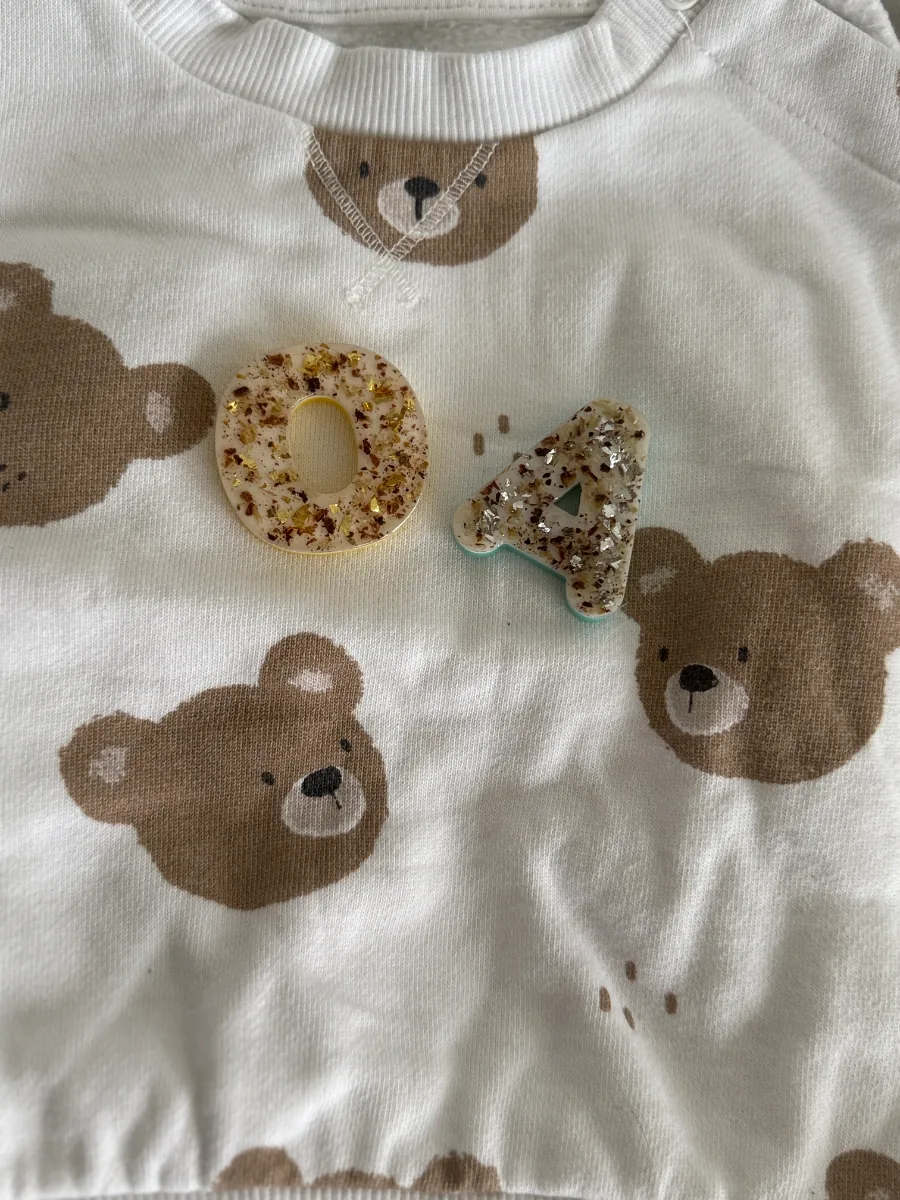 Lettres O et A au cordon ombilical posées sur un pull à motif ourson