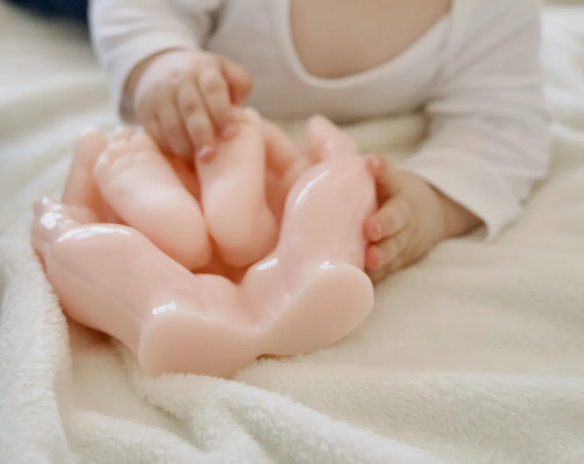 Bébé posant les mains sur le moulage en résine rose de ses pieds et de ses mains