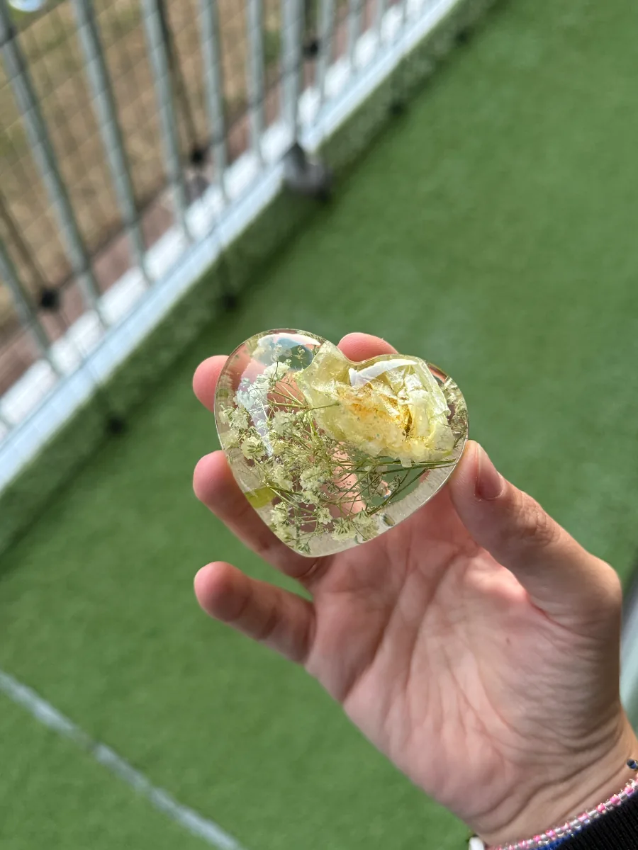 Cœur en résine avec fleurs de bouquet de mariée tenu dans la main
