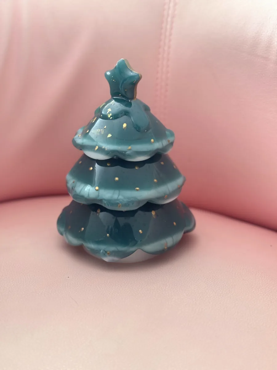 Sapin de Noël vert à pois dorés posé sur un fauteuil rose
