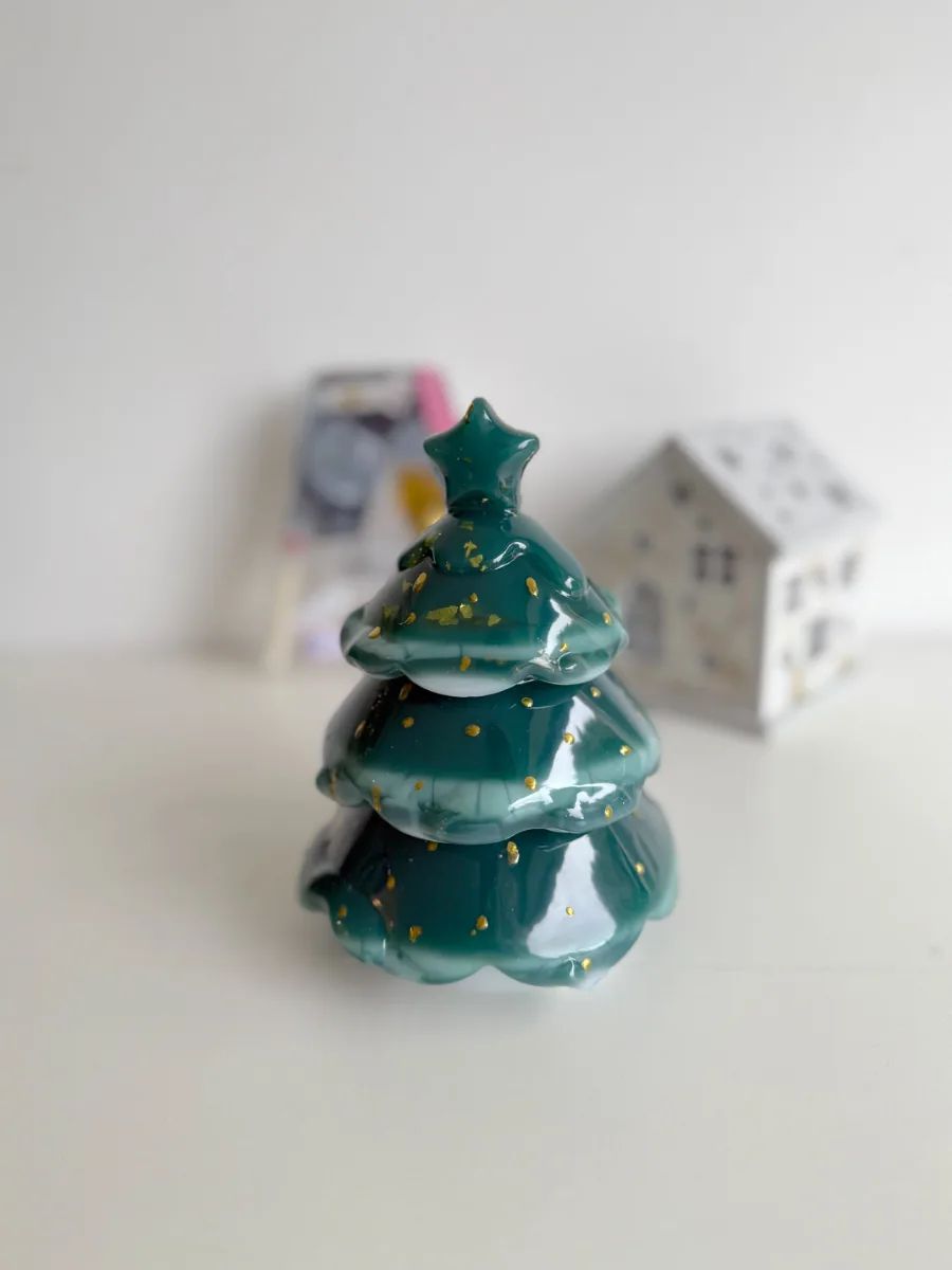 Sapin boîte à bijoux vert à étoile dorée devant une maison blanche