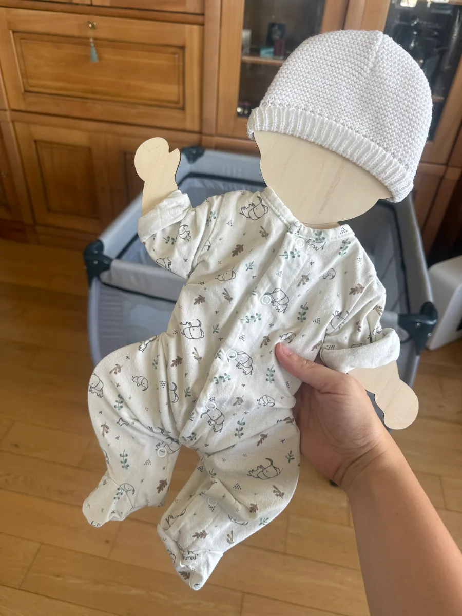 Support souvenir en bois habillé du pyjama et du bonnet de naissance, tenu en main