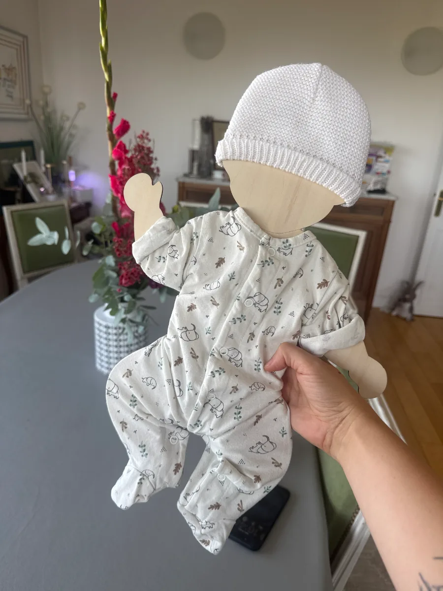 Support des vêtements de naissance en bois présenté dans un salon