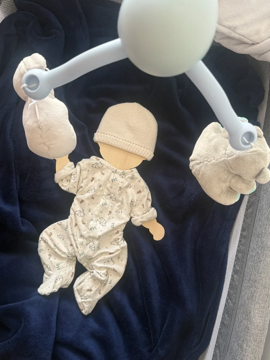Support souvenir des vêtements de naissance posé sous un mobile de bébé