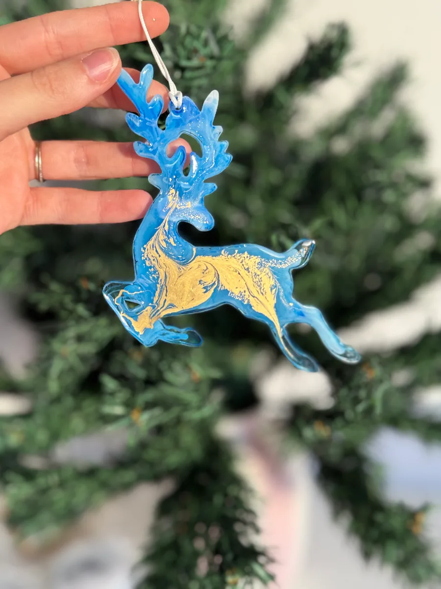 Cerf de Noël en résine bleu roi et or tenu en main