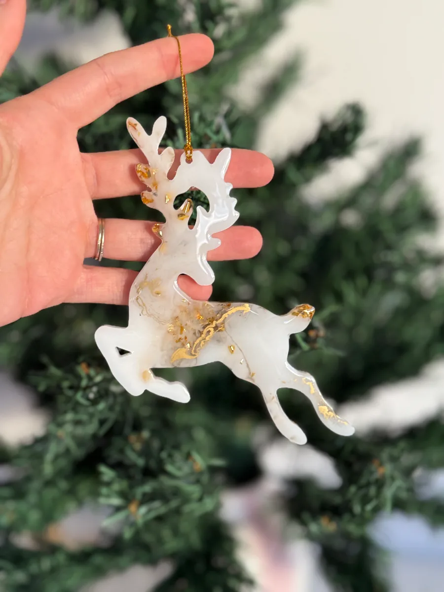 Suspension cerf blanc à feuilles d'or tenue en main
