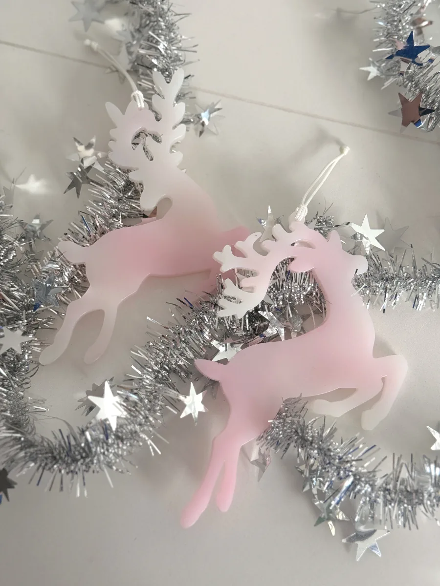 Cerfs de Noël en résine rose sur une guirlande argentée et des étoiles