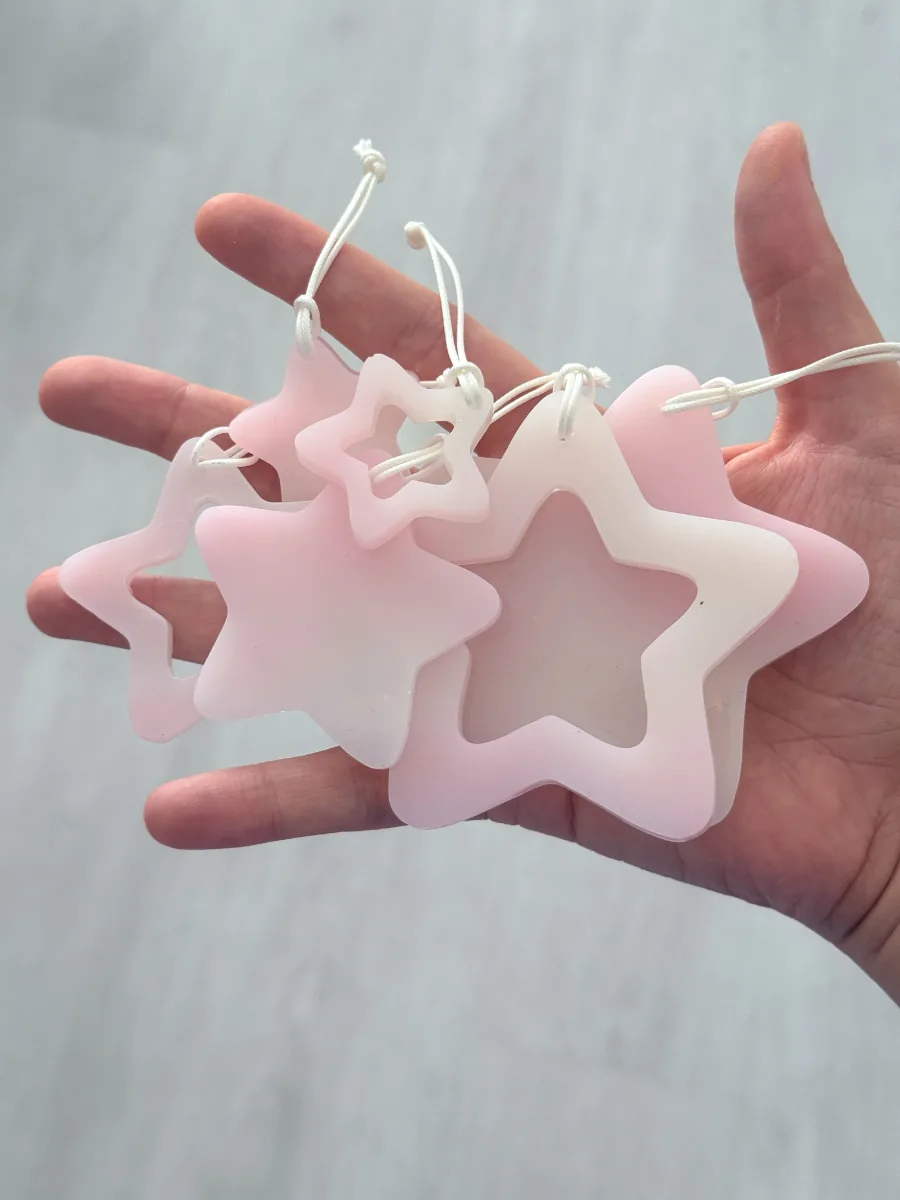 Lot d'étoiles de Noël en résine rose et blanche tenues dans la main