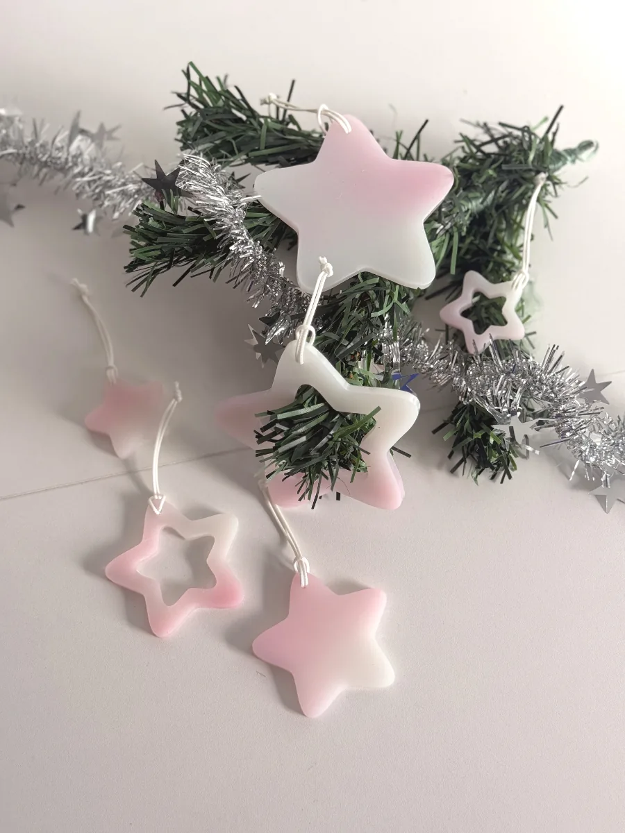 Étoiles de Noël en résine rose et blanche, pleines et ajourées, sur une guirlande argentée