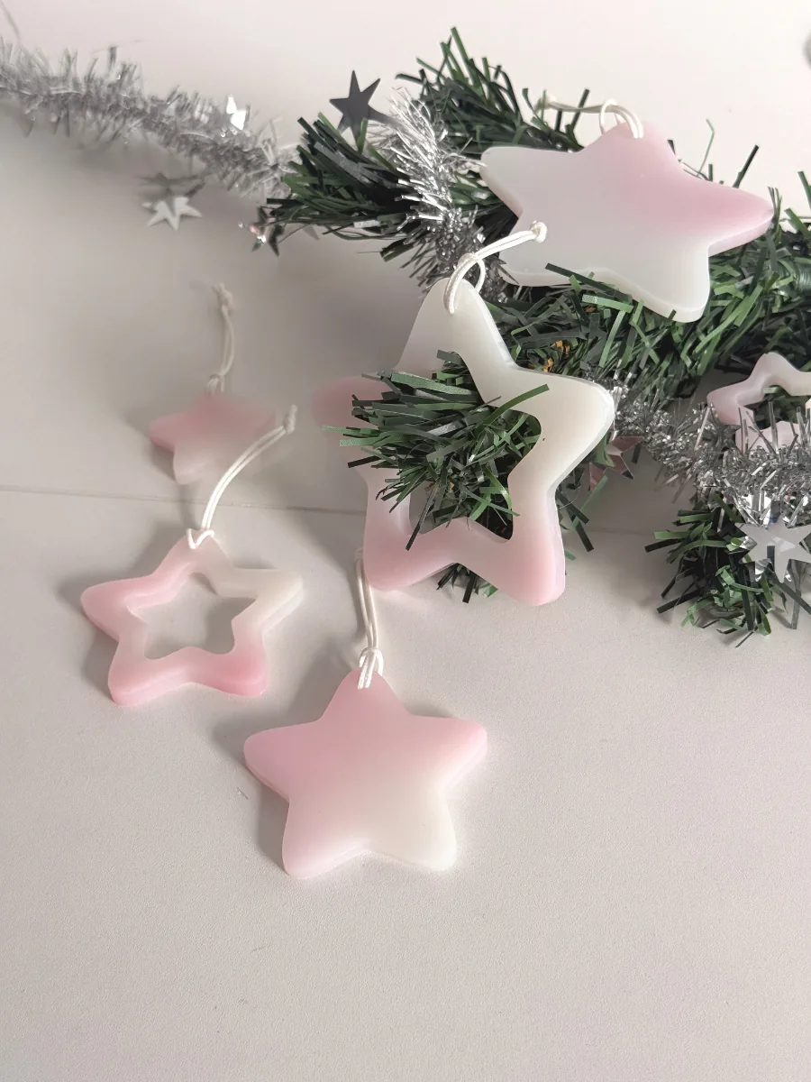Étoiles en résine rose et blanche accrochées à une branche de sapin