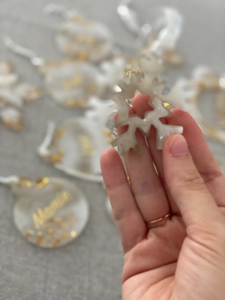 Flocon de Noël en résine blanche tenu au-dessus de boules personnalisées