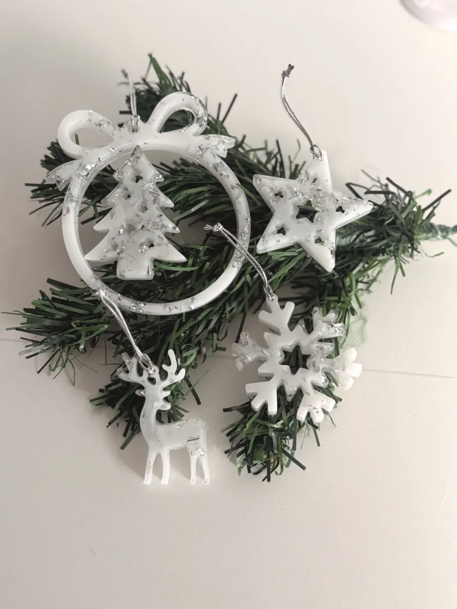 Suspensions de Noël blanches en résine posées sur des branches de sapin