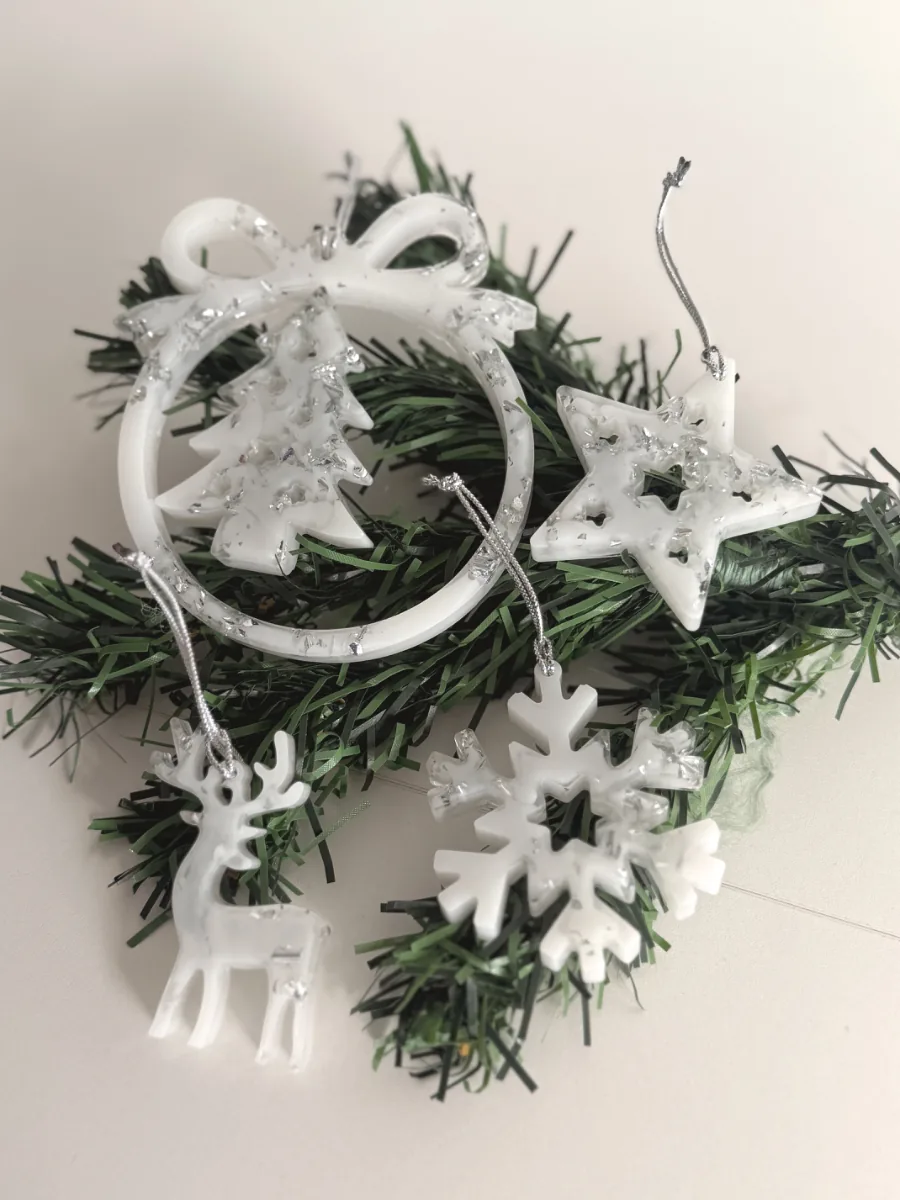 Boule à nœud avec sapin, cerf et flocon en résine blanche sur des branches de sapin