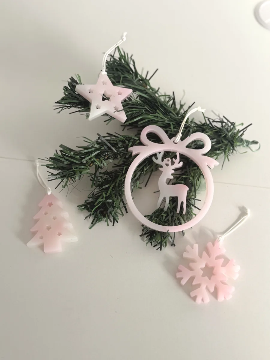Suspensions de Noël roses en résine sur des branches de sapin